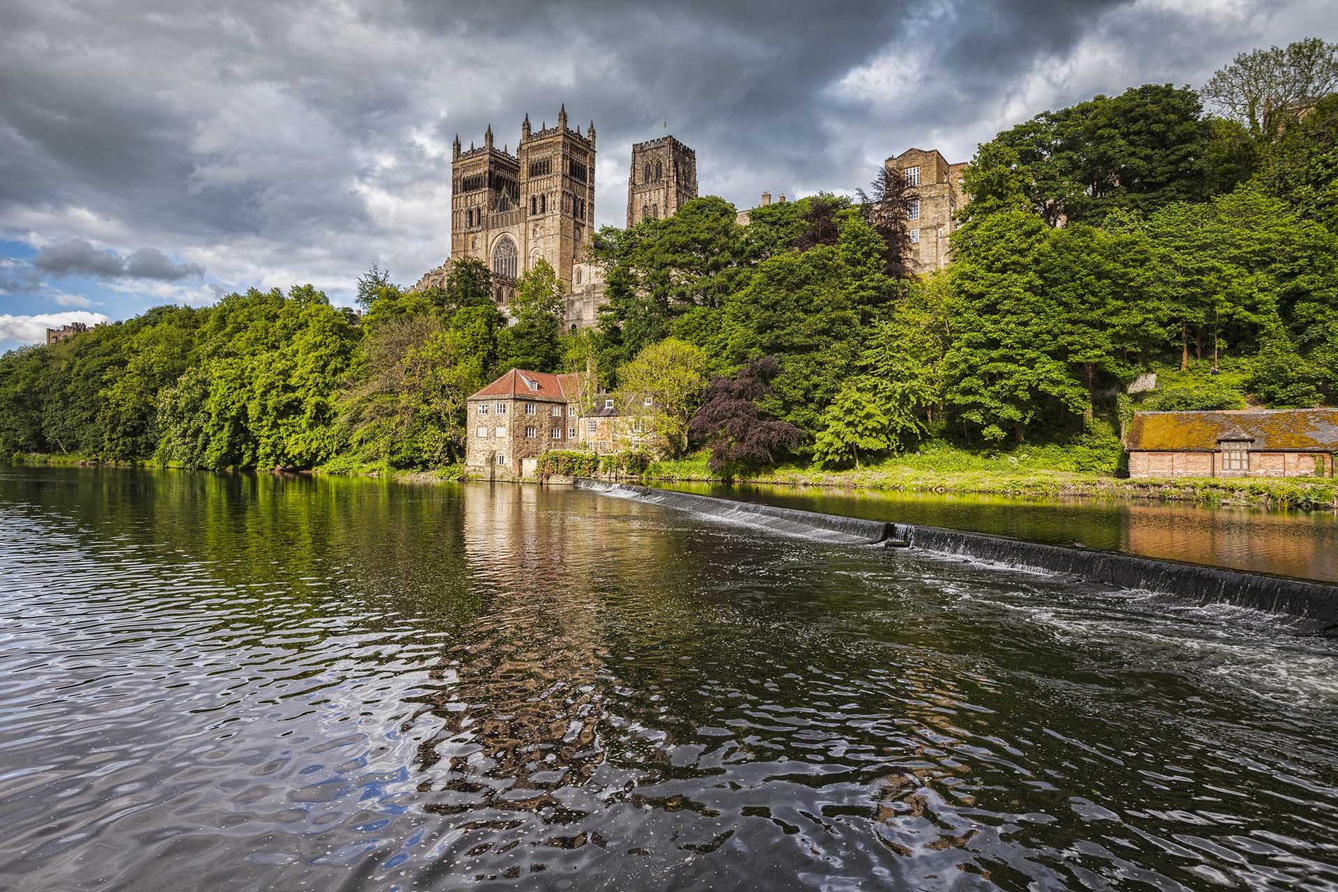 Durham Cathedral and the River Wear under a dramatic stormy sky.